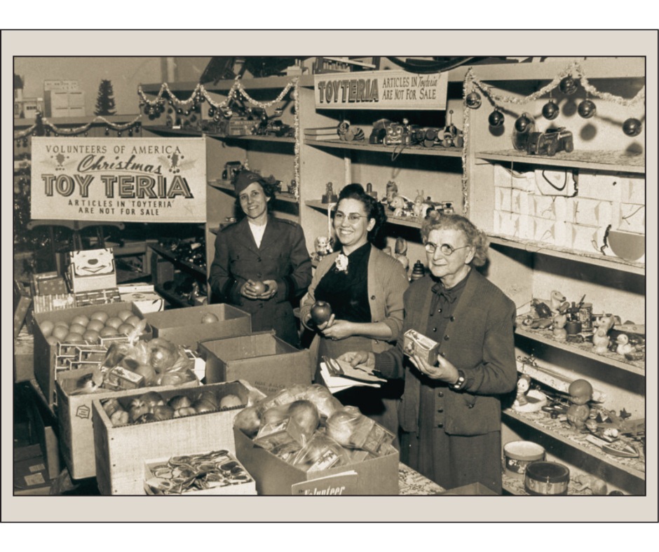 Vintage black and white photo of two women with a room full of donated toys for the holidays